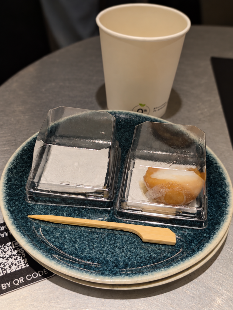 Assiette en céramique bleue avec une bouchée dans son emballage ouvert, une petite fourchette et un gobelet en arrière-plan.